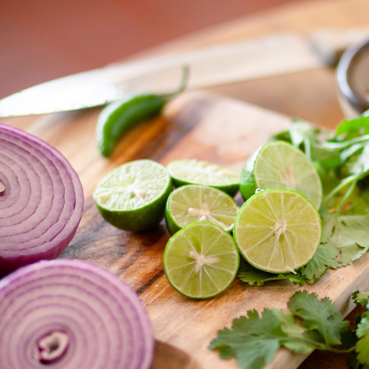 Limes, cilantro and red onion cut on the board.