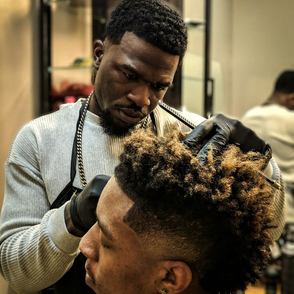 A barber shaping a client's fade